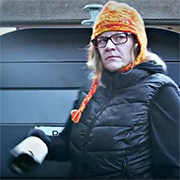Une dame avec l'air peu commode se tient devant un container de tri