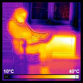 Une grand-mère assise sur une chaise près d'un radiateur et d'une fenêtre vue en infra-rouge